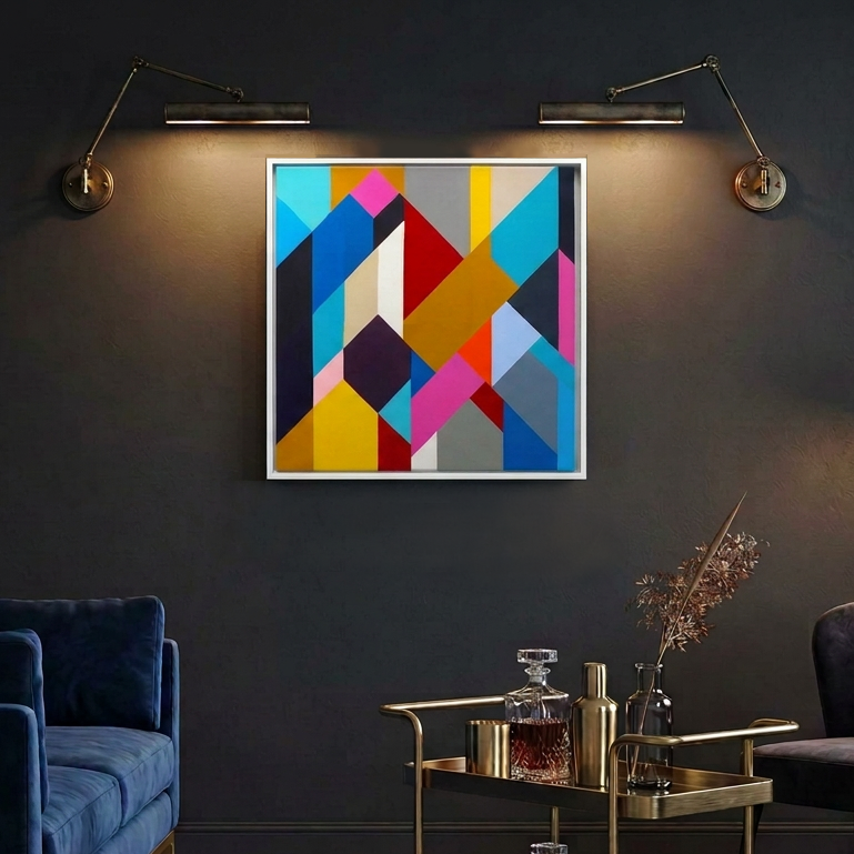 Geo Blocks 2 - A framed abstract geometric wall art painting with a white frame hangs on a dark charcoal wall in a styled living room setting, illuminated by two wall-mounted brass sconces. The artwork features a vibrant mix of blue, yellow, pink, orange, red, and gray shapes.