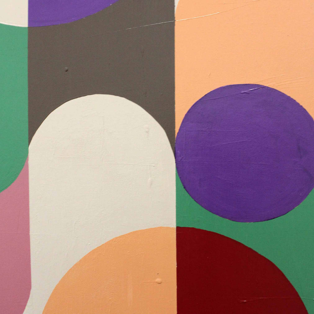 Close up of abstract geometric wall art by Andy Watt featuring overlapping circles and arcs in purple, green, peach, white, dark gray, pink, and red. 