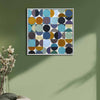 A white framed abstract spot painting featuring white squares and contrasting circles in shades of blue, teal, purple, brown, black, and mustard hanging on a living room wall.