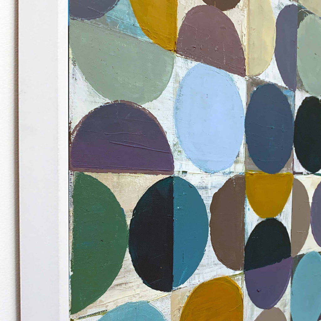 Close-up side view of an abstract geometric painting showing a white frame the painting features overlapping semi-circles and circles in muted colours including blue, green, purple, yellow, brown, and black on a light background.