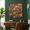 A square abstract canvas painting with a vibrant splatter pattern in red, yellow, white, and black, displayed on a dark green wall above a wooden desk with a brown leather chair.
