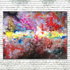 A large abstract canvas wall art hand painted and featuring a vibrant, textured composition of red, pink, yellow, blue, white, and dark brown brushstrokes, displayed on a white brick wall.