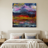 Flamingo Sunset - A square abstract canvas painting with a colourful sunset-like composition hangs on a beige wall above a neatly made bed with neutral bedding and bedside lamps.