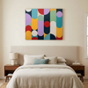 Geo Pop Lines No 1  A colourful abstract geometric wall art painting hangs above a neatly made bed in a modern bedroom setting. The artwork features vertical and circular shapes in yellow, red, purple, teal, green, and navy on a cream background.