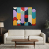 Geo Pop Lines No 1 - A colourful abstract canvas painting with vertical bars and overlapping circles in red, yellow, teal, purple, green, cream, and navy, displayed on a dark charcoal wall above a cream coloured sofa with a wooden coffee table in front.