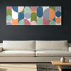 Geo Pop Lines No 8 - A modern living room setting featuring a wide canvas wall art painting with an abstract geometric pattern of colourful arches and circles, hung on a dark charcoal wall above a light beige sofa.