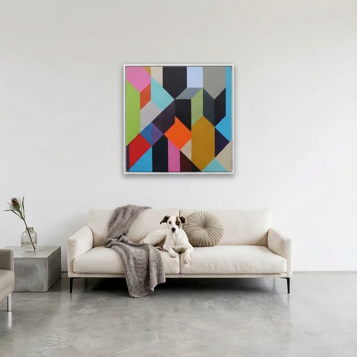 Geo Blocks 1 - A colourful geometric wall art painting hangs above a cream sofa in a modern living room. The artwork features an abstract multi-colour pattern of triangles and polygons in pink, blue, orange, yellow, green, black, and grey.