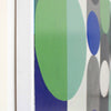 Close-up of a framed abstract art painting featuring large green, blue, grey, and white geometric circles on a white background.