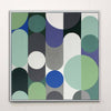 abstract art painting hanging in a studio wall featuring large green, blue, grey, and white geometric circles on a white background framed in a white floating frame.