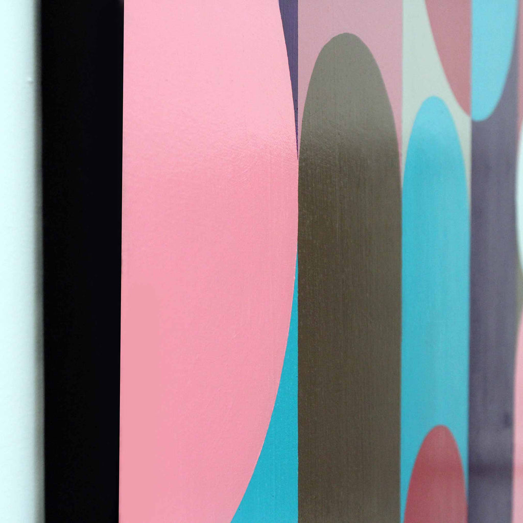 Abstract framed wall art featuring bold geometric shapes in pink, turquoise, olive green, and dark purple, shown in a close-up view with a black frame edge visible on the left.