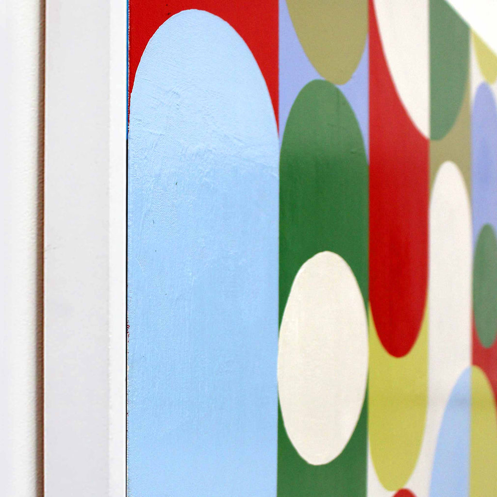 Close-up of a colourful abstract wall art painting with overlapping rounded arches and circles in light blue, green, red, yellow, and white, shown against a white wall.