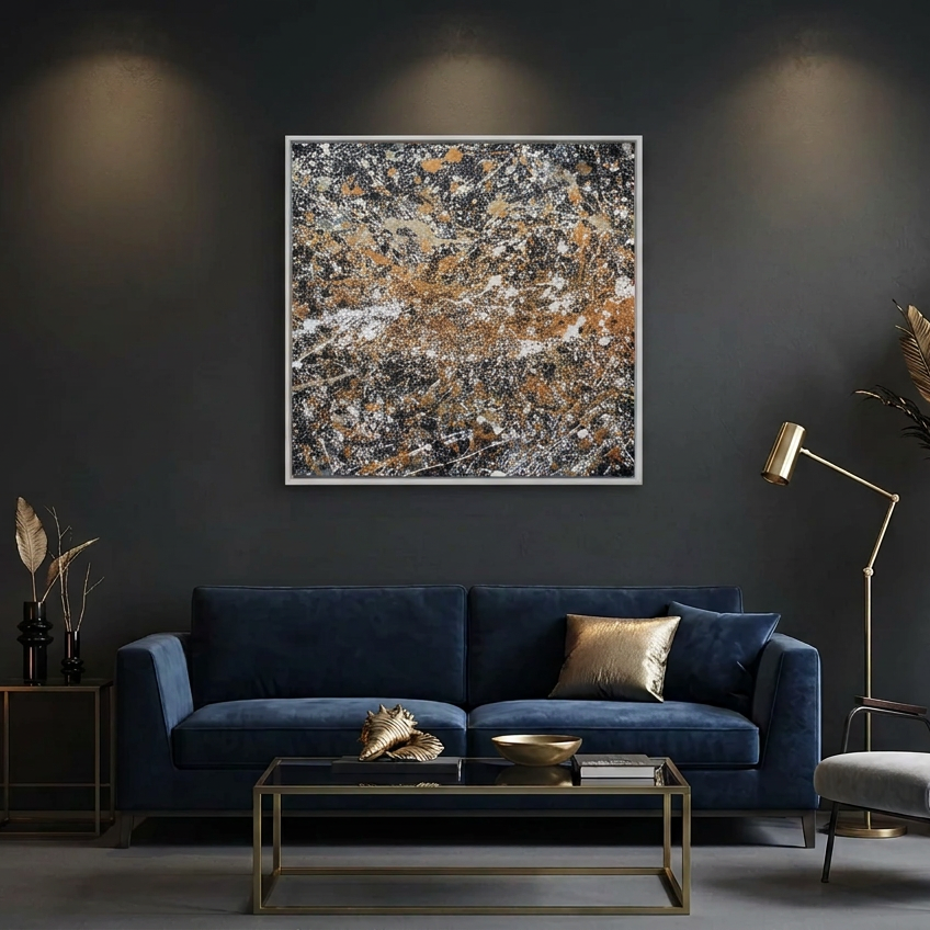 A square framed abstract wall art painting with a textured marbled pattern in black, white, grey, and warm gold-brown tones, displayed above a dark blue velvet sofa in a modern living room setting.