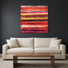 Indian Summer - A square abstract canvas painting with vibrant red, orange, yellow, and pink horizontal brushstrokes, displayed on a dark grey wall above a modern cream coloured sofa with a wooden coffee table.