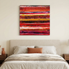 Indian Summer  - A square abstract canvas Painting with horizontal red, orange, yellow, and dark brushstrokes, displayed on a beige wall above a neatly made bed in a bedroom setting.