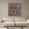 Kinetic Flow - A square framed abstract painting with a dense splatter pattern of red, blue, white, and black paint hangs on a beige wall above a light cream sofa in a modern living room setting.