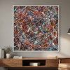Kinetic Flow - A square abstract wall art painting with a white frame, featuring a dense splatter pattern of red, blue, black, white, and orange paint, displayed in a modern living room setting above a wooden console table.