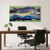 An abstract landscape canvas wave painting called Malva Wave with vibrant greens, blues, purples, and golds, displayed on a neutral wall above a wooden desk with two black office chairs.