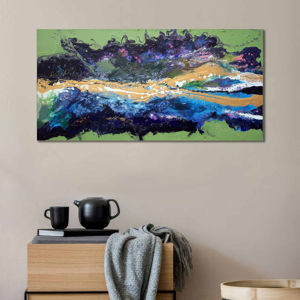 Malva Wave is a abstract canvas wall art featuring a landscape-like composition with green, blue, purple, black, and gold brushstrokes, displayed above a wooden side table in a neutral room setting.