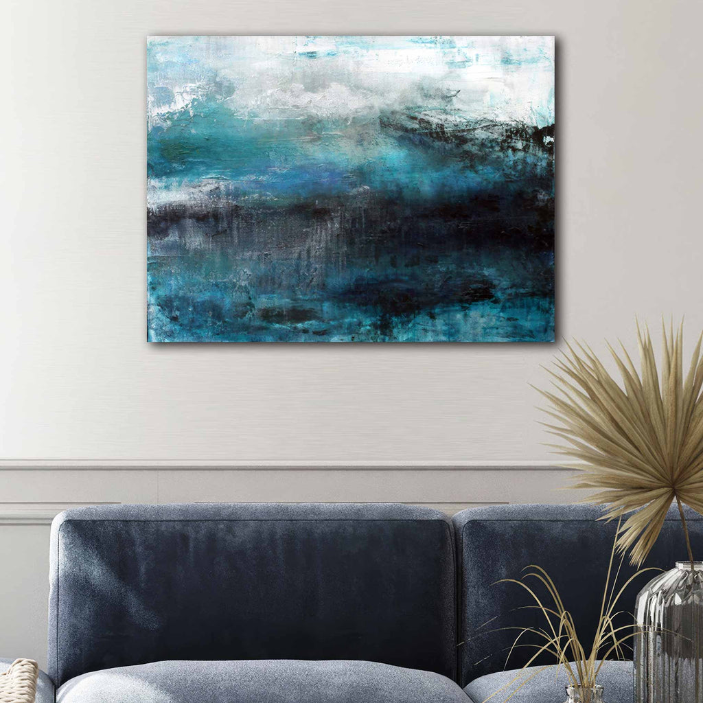 Abstract canvas wall art painting featuring textured blue, teal, white, and black brushstrokes, displayed above a grey sofa in a modern living room setting.