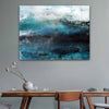 Abstract canvas wall art painting featuring textured brushstrokes of teal, blue, black, and white, displayed on a grey wall above a wooden dining table with chairs and a vase.
