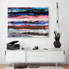A large abstract canvas painting with horizontal bands of blue, pink, red, black, and white hangs on a white wall above a modern white sideboard with a record player, books, headphones, and a potted plant.
