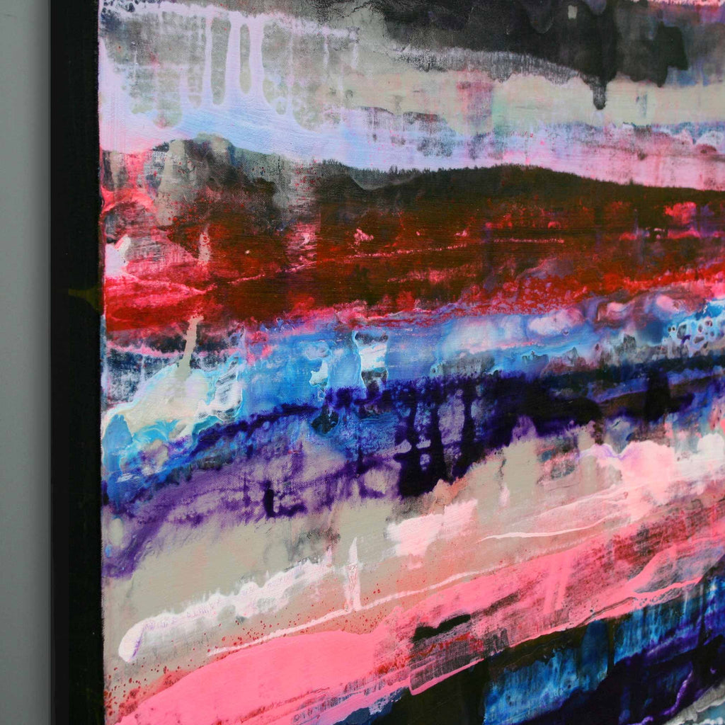Close up detail of abstract canvas wall art featuring expressive horizontal brushstrokes in red, pink, blue, black, white, and grey, shown hanging against a light grey wall.