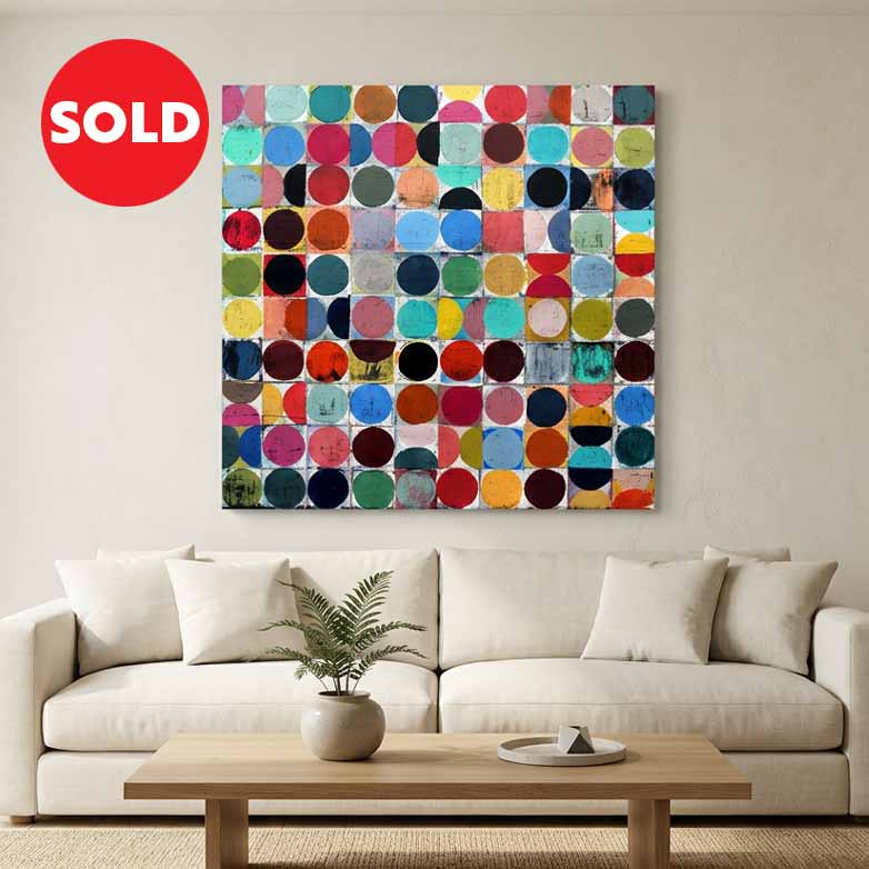 Vintage spheres No 10 - A square abstract canvas painting featuring a sold circle in red with white text top left of image, A colourful grid of painted blocks and circles in various hues, displayed on a beige wall above a modern white sofa in a bright, minimalist living room.