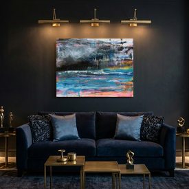 A large abstract canvas seascape painting of a storm at sea in vibrant blue, pink, yellow, and grey tones hangs on a dark charcoal wall above a navy blue velvet sofa in a modern living room setting.