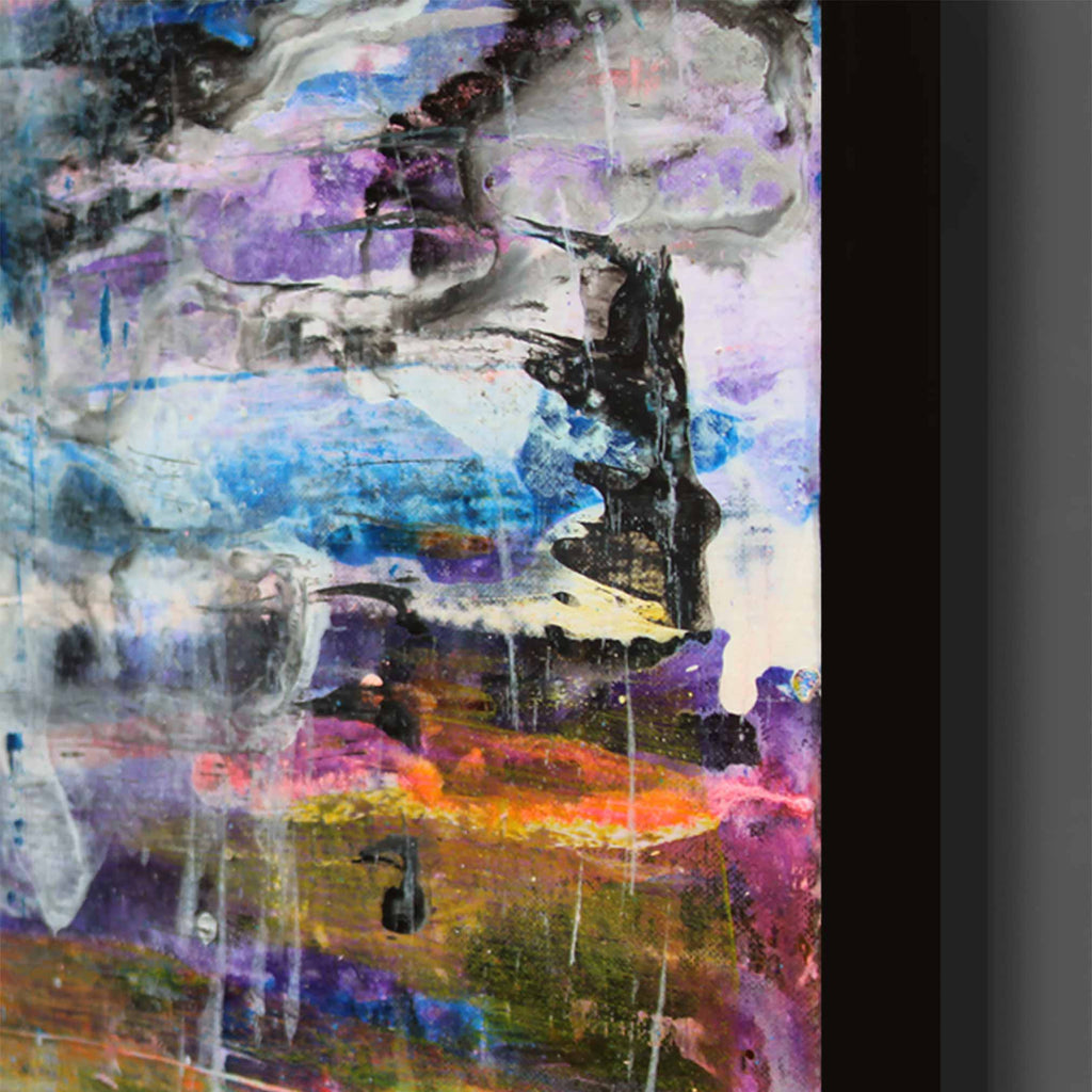 Close up of abstract canvas wall art featuring expressive brushstrokes and drips in purple, blue, black, white, orange, pink, and green tones, shown with a dark frame edge on a neutral background.