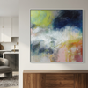 Summer Showers - An abstract canvas painting with vibrant splashes of green, yellow, blue, pink, and orange, displayed on a light grey wall in a modern living space above a wooden console table.