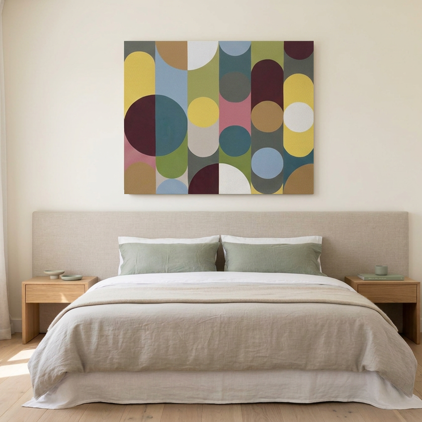 Geo Pop Lines No 13 - A large abstract canvas wall art painting with geometric circles and arcs in muted yellow, blue, green, pink, brown, and white, displayed above a double bed in a modern bedroom setting.