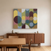 Geo Pop Lines No 13 - A large abstract canvas wall art painting with geometric circles and arcs in muted yellow, blue, green, pink, brown, and white, displayed above a mid-century modern wooden sideboard in a dining room setting.