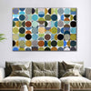 A large rectangular canvas wall art piece featuring an abstract pattern of overlapping circles in multiple colors, displayed above a beige sofa in a modern living room setting.