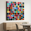 Vintage Spheres No 10 in a modern dining room setting - A square canvas wall art painting featuring a colourful grid of painted circles, displayed in a modern dining room setting above a light wood sideboard and dining table.