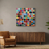 Vintage spheres No 10 - A square abstract canvas painting featuring a colourful grid with painted multi coloured circles, displayed on a beige wall above a modern mood sideboard, with brown leather chair to the left in a minimalist living room.