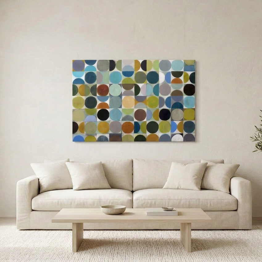 Vintage Spheres No 2 - A large rectangular wall art painting with a grid of colourful circles in blue, green, yellow, brown, black, and grey tones, displayed above a light beige sofa in a bright living room.