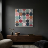 Vintage Spheres No 3 - A square framed wall art painting featuring a grid of painted circles in muted pink, teal, navy, red, grey, and orange tones, displayed above a dark wood console in a modern room setting.