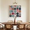 Vintage Spheres No 3 - A large square abstract wall art painting with colourful circles hangs above a wooden dining table and woven-back chairs in a softly lit dining room.