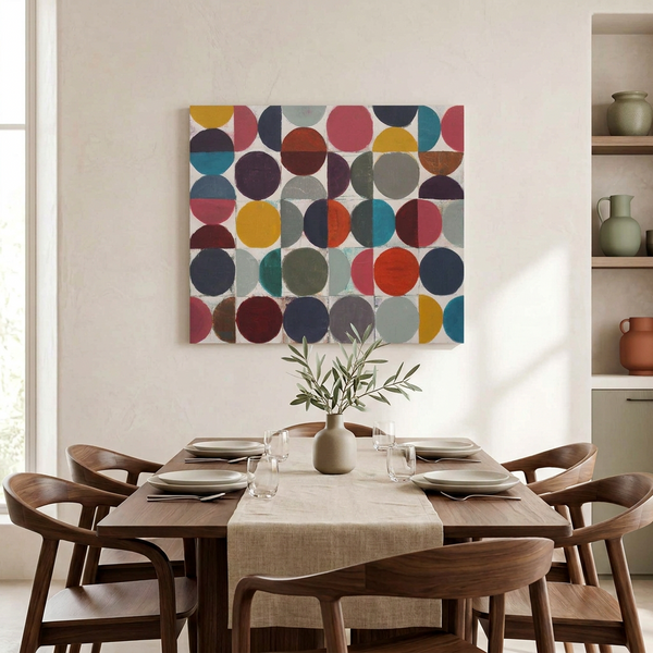 Vintage Spheres No 5 - A square canvas wall art painting featuring a colourful geometric pattern of overlapping circles and semi-circles in pink, yellow, blue, red, grey, and brown, displayed on a beige wall above a dining table with wooden chairs.