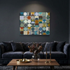 Vintage Spheres 1 - A modern living room setting featuring a  abstract canvas painting with a grid of colourful circles in shades of blue, green, yellow, orange, and beige, hung on a dark grey wall above a dark blue velvet sofa.