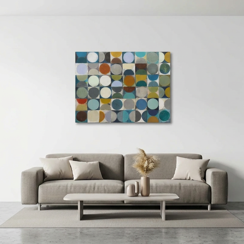 Vintage Spheres 1 - A abstract wall art painting with a grid of multi-coloured circles in blue, teal, green, brown, beige, and grey, displayed above a modern grey sofa in a minimalist living room setting.