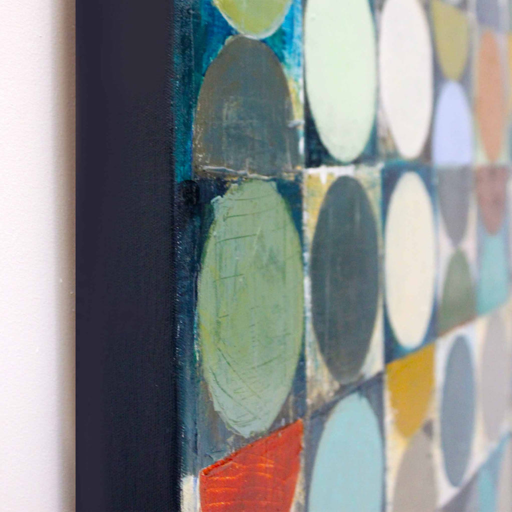 Close-up of a framed abstract geometric painting featuring overlapping circles in muted teal, green, cream, gray, yellow, and red tones.
