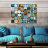 A square abstract canvas print with a grid of colorful circles in blue, teal, yellow, brown, and gray, hanging on a rustic wood-paneled wall above a turquoise sofa with decorative vases and pillows.