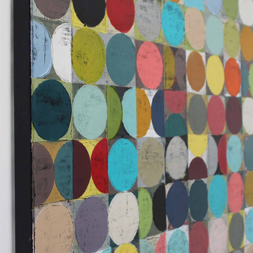 A close-up side view of a abstract artwork featuring a grid of colourful circles and squares in many hues including blue, red, yellow, green, pink, black, and beige.