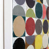 Close-up of a framed abstract geometric painting featuring bold circular and semi-circular shapes in red, yellow, black, gray, beige, green, and white.