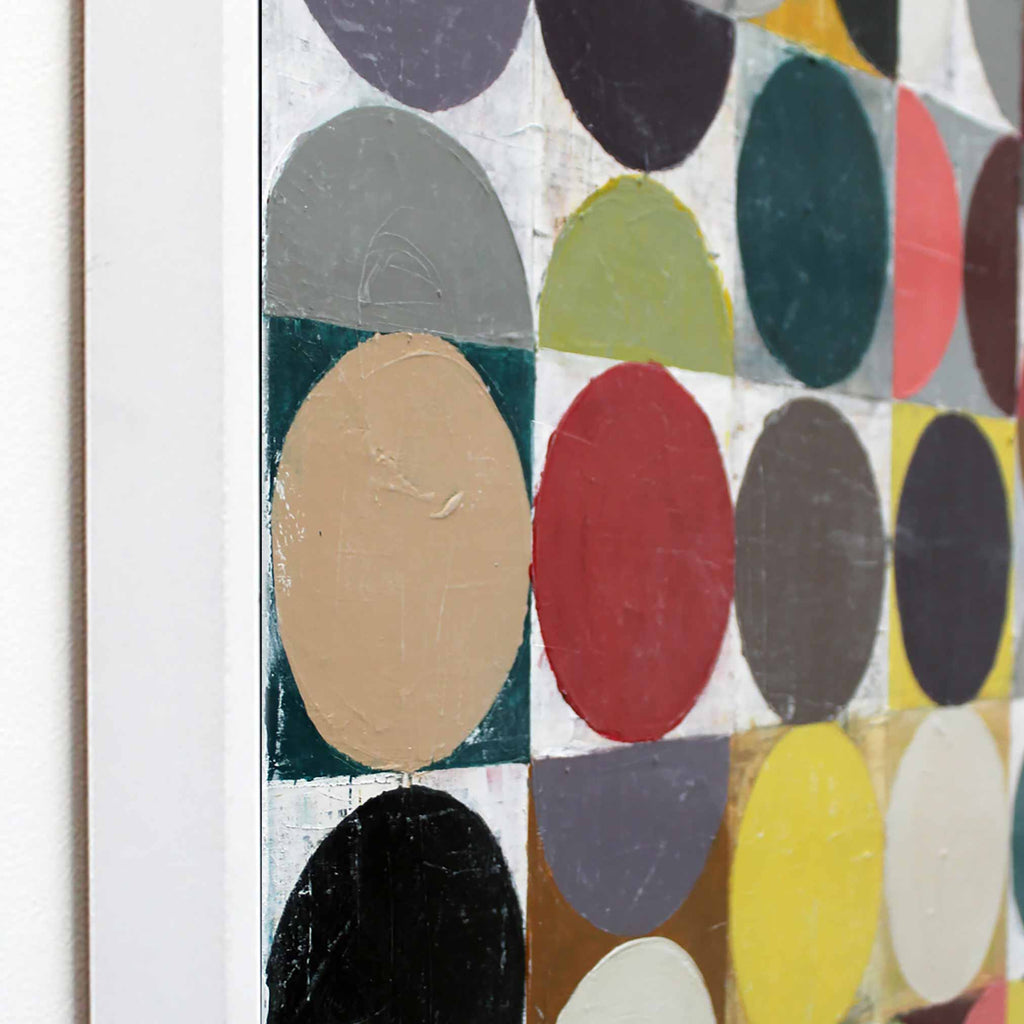 Close-up of a framed abstract geometric painting featuring bold circular and semi-circular shapes in red, yellow, black, gray, beige, green, and white.
