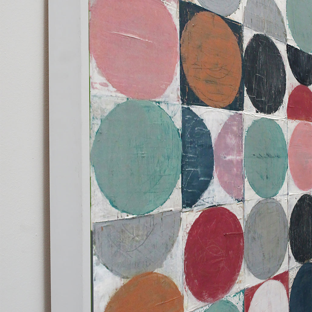 Close-up of a framed abstract artwork featuring large textured circles and half-circles in pink, teal, orange, red, gray, black, and white.