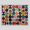 A framed abstract geometric wall art print featuring a grid of colored circles on a white background, shown against a neutral gray backdrop.