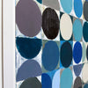 Abstract geometric wall art painting featuring a grid of painted circles and half-circles in shades of blue, teal, navy, grey, black, and off-white, mounted on a white wall.