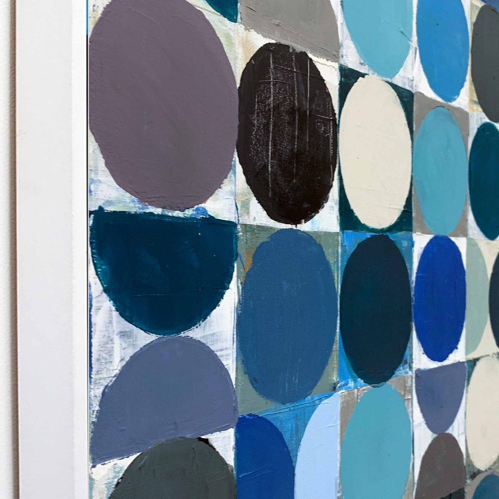Abstract geometric wall art painting featuring a grid of painted circles and half-circles in shades of blue, teal, navy, grey, black, and off-white, mounted on a white wall.